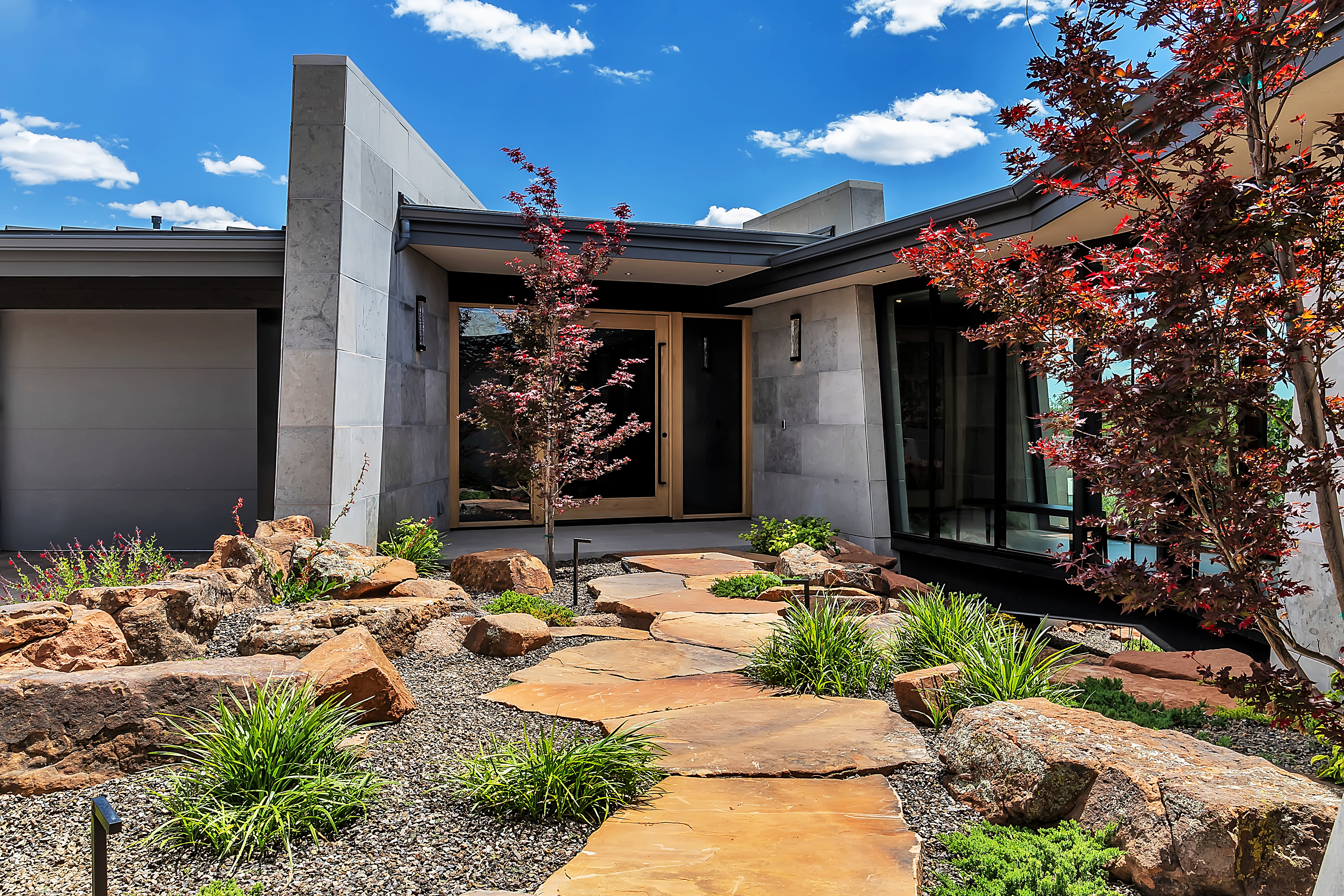Luxury home entrance with Japanese maple trees and stone pathway